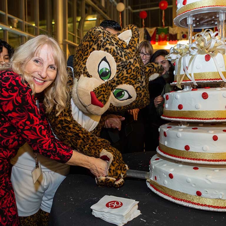 Director of the 50th Anniversary Christine Fitzpatrick and Jazzy the Jaguar mascot cut the tiered 50th Anniversary cake.