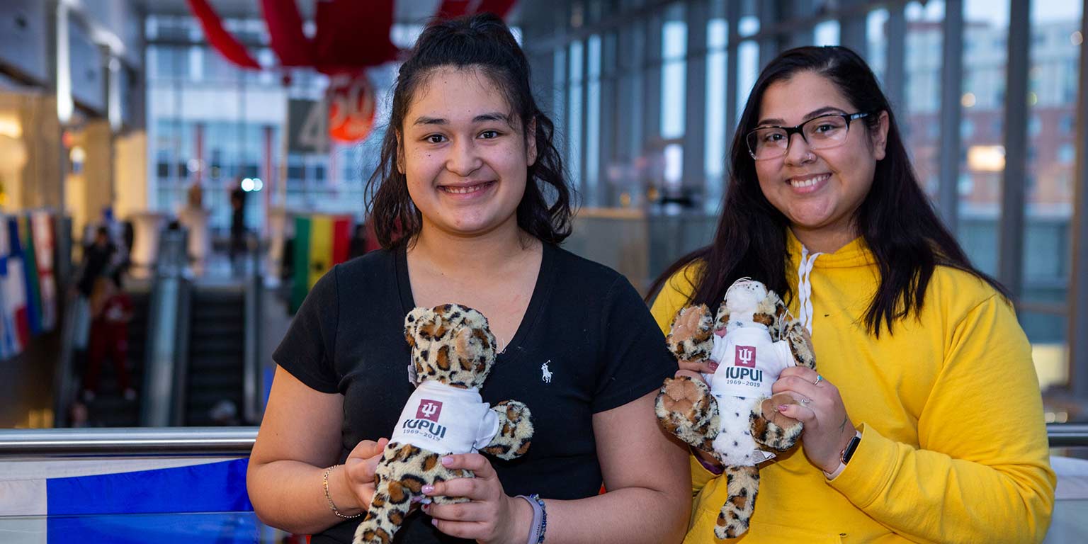 Two girls stand with their stuffed jaguars.
