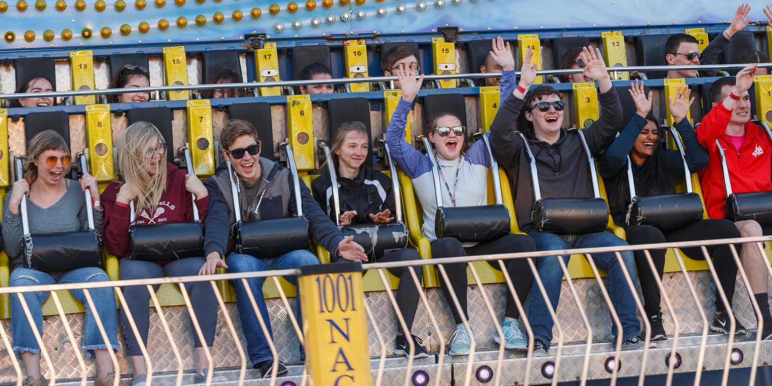 Students raise their hands as they return from the giant drop ride at Jagapalooza.